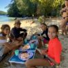 A smiling family on the the beach enjoying a bbq in a turquoise lagoon