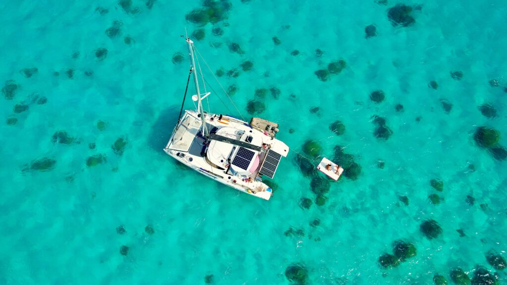 Catamaran anchored in the turquoise lagoon of the Tuamotu Islands during a multi-atoll sailing cruise