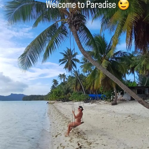 Traveler swinging on a beach swing in French Polynesia at sunset